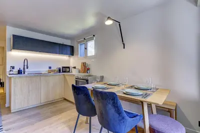 a kitchen with a wooden table and blue chairs at Ancelles - Cocon 1CH Balcon Parking HomeCine CentrePraz in Chamonix-Mont-Blanc