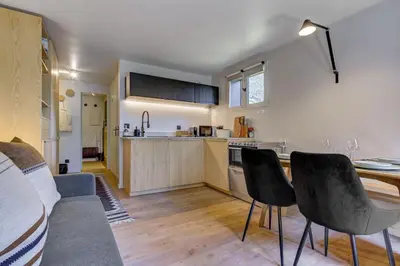 a kitchen with two chairs and a table in a room at Ancelles - Cocon 1CH Balcon Parking HomeCine CentrePraz in Chamonix-Mont-Blanc
