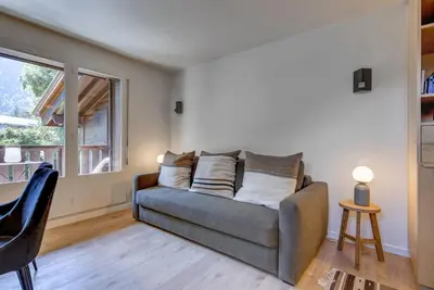 a living room with a couch and a window at Ancelles - Cocon 1CH Balcon Parking HomeCine CentrePraz in Chamonix-Mont-Blanc