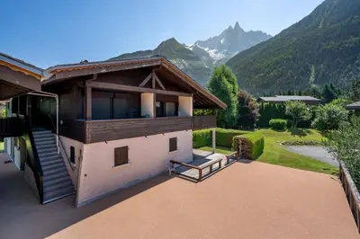 a house with a balcony with mountains in the background at Ancelles - Cocon 1CH Balcon Parking HomeCine CentrePraz in Chamonix-Mont-Blanc