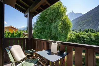 a porch with chairs and a table and a view of mountains at Ancelles - Cocon 1CH Balcon Parking HomeCine CentrePraz in Chamonix-Mont-Blanc