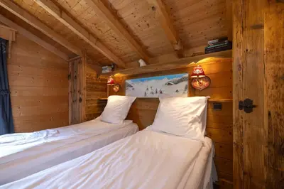two beds in a cabin with wooden walls at Tete aux Vents - Chalet Familial Centre Vue Randos Parking in Chamonix-Mont-Blanc