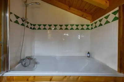 a white bath tub in a bathroom with a tile wall at Tete aux Vents - Chalet Familial Centre Vue Randos Parking in Chamonix-Mont-Blanc