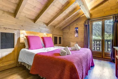 a bedroom with a large bed with pink pillows at Michka - Chalet 500m Flegere Cheminee Jardin Vue 180 in Chamonix-Mont-Blanc