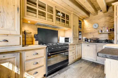 a kitchen with wooden cabinets and a stove at Michka - Chalet 500m Flegere Cheminee Jardin Vue 180 in Chamonix-Mont-Blanc