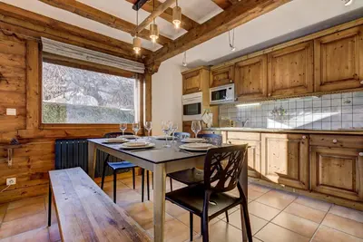 a dining room with a table and chairs in a kitchen at Aurore - Cosy 74m2 Vue Jardin Remontee 250m Parking Bus in Chamonix-Mont-Blanc