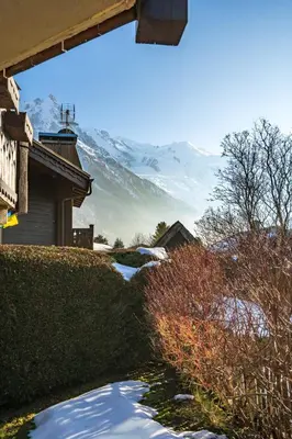 a snow covered yard with a mountain in the background at Aurore - Cosy 74m2 Vue Jardin Remontee 250m Parking Bus in Chamonix-Mont-Blanc