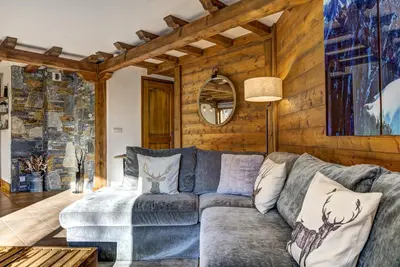 a living room with a gray couch and wooden walls at Aurore - Cosy 74m2 Vue Jardin Remontee 250m Parking Bus in Chamonix-Mont-Blanc