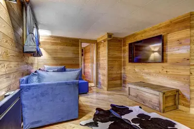 a room with a blue couch in a room with wooden walls at Passon - Appart 2CH 93m2 Sauna 300m Grand Montets Vue in Chamonix-Mont-Blanc