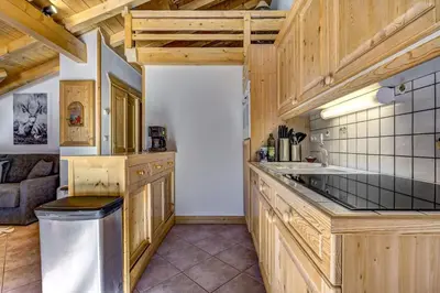 a kitchen with wooden cabinets and a counter top at Passon - Appart 2CH 93m2 Sauna 300m Grand Montets Vue in Chamonix-Mont-Blanc
