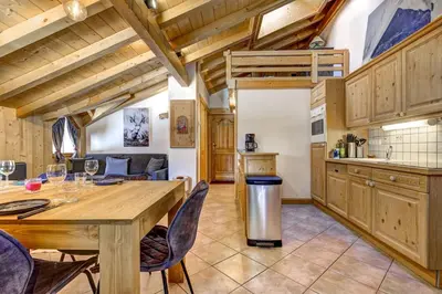 a kitchen and dining room with a wooden table and chairs at Passon - Appart 2CH 93m2 Sauna 300m Grand Montets Vue in Chamonix-Mont-Blanc