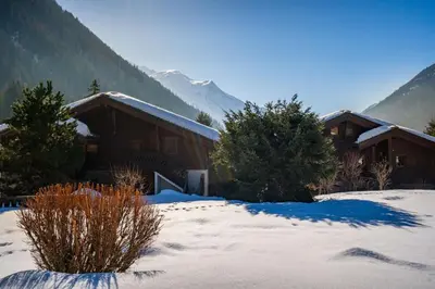 a house in the snow with mountains in the background at Passon - Appart 2CH 93m2 Sauna 300m Grand Montets Vue in Chamonix-Mont-Blanc