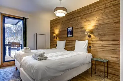 two beds in a room with a wooden wall at Brume - 2CH 2SDB Vues Remontees 400m Garage SPA in Les Houches