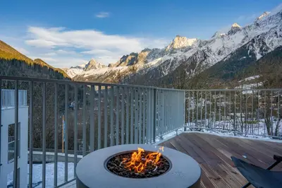 a fire pit on a deck with a view of mountains at Brume - 2CH 2SDB Vues Remontees 400m Garage SPA in Les Houches