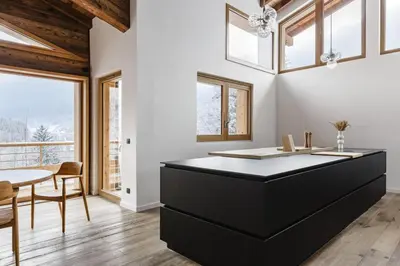 a kitchen with a black island and a table at 7 Summits - Chalet 230m2 Salon Cathedrale Vues Cheminee in Les Houches