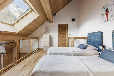 a attic bedroom with two beds and a window at Ciel - Duplex 100m2 Centre Vues Parking 3CH 3SDB in Chamonix-Mont-Blanc