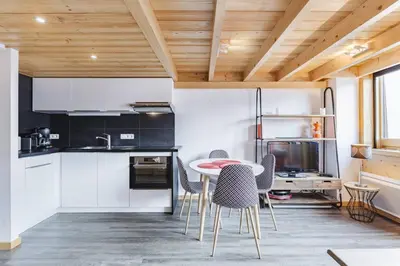 a kitchen with white cabinets and a table and chairs at Grand Roc - Cosy Duplex Grands Montets Balcon Vue Parking in Chamonix-Mont-Blanc