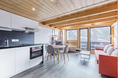 a kitchen and living room with a table and chairs at Grand Roc - Cosy Duplex Grands Montets Balcon Vue Parking in Chamonix-Mont-Blanc