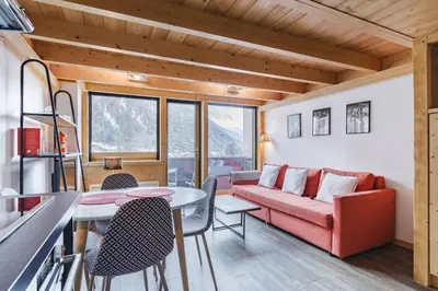 a living room with a red couch and a table at Grand Roc - Cosy Duplex Grands Montets Balcon Vue Parking in Chamonix-Mont-Blanc