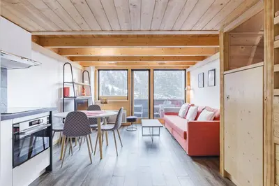 a kitchen and living room with a red couch and a table at Grand Roc - Cosy Duplex Grands Montets Balcon Vue Parking in Chamonix-Mont-Blanc