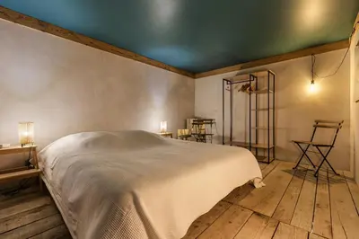 a bedroom with a white bed and wooden floors at Loft Bellevue Remonte Centre Piscine Parking in Les Houches