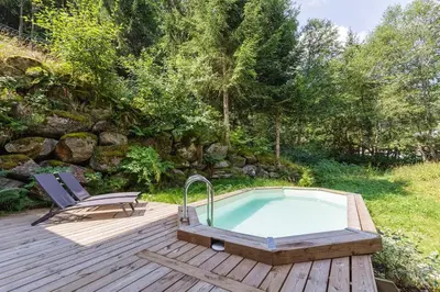 a hot tub on a wooden deck with a chair at Loft Bellevue Remonte Centre Piscine Parking in Les Houches