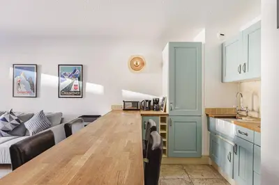 a kitchen and living room with a table and a couch at Beckett - Cocon familial Central Balcon Vue 200m Gare in Chamonix-Mont-Blanc