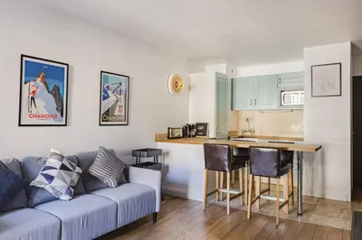 a living room with a couch and a kitchen at Beckett - Cocon familial Central Balcon Vue 200m Gare in Chamonix-Mont-Blanc