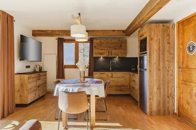 a kitchen with wooden cabinets and a table with chairs at Pecles - Apt 2CH Balcon Vue Gaillands 500m Centre 1km in Chamonix-Mont-Blanc