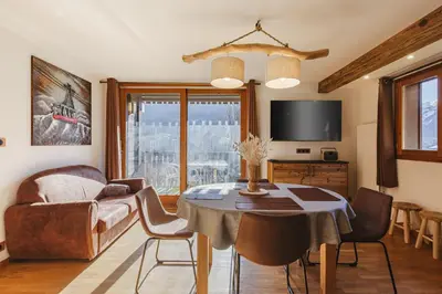 a living room with a table and chairs and a television at Pecles - Apt 2CH Balcon Vue Gaillands 500m Centre 1km in Chamonix-Mont-Blanc