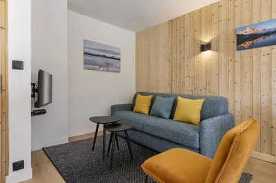 a living room with a blue couch and a table at Hautes Aiguilles - Apart 2CH Vues Garage 5mn Grands Montets in Chamonix-Mont-Blanc