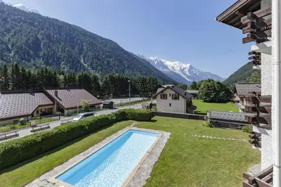 a swimming pool in the yard of a house with mountains at Hautes Aiguilles - Apart 2CH Vues Garage 5mn Grands Montets in Chamonix-Mont-Blanc