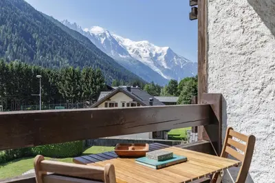a wooden table and chairs on a balcony with a mountain at Hautes Aiguilles - Apart 2CH Vues Garage 5mn Grands Montets in Chamonix-Mont-Blanc