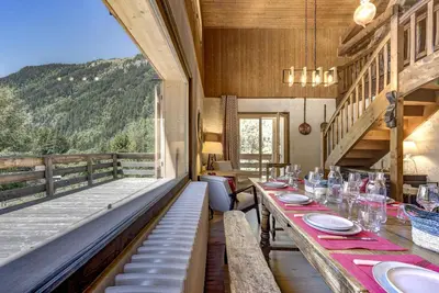 a dining room with a table and a balcony at Le 111 - Chalet 4CH Calme Vue Pano 5mn Grands Montets in Chamonix-Mont-Blanc