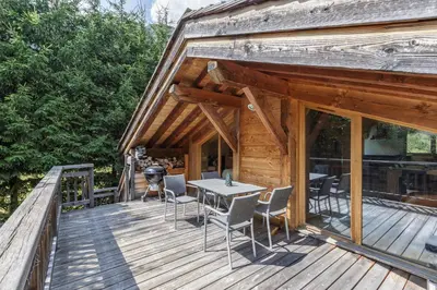 a wooden deck with a table and chairs on it at Whisky - Chalet 150m2 Calme Sauna Jacuzzi in Chamonix-Mont-Blanc