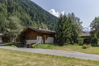 a house in the mountains with a road next to it at Whisky - Chalet 150m2 Calme Sauna Jacuzzi in Chamonix-Mont-Blanc