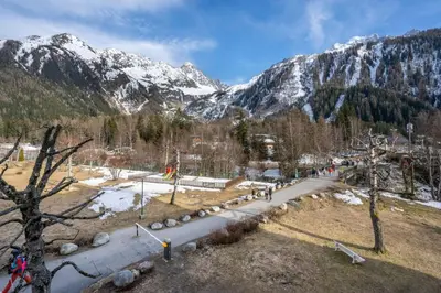 a group of people walking down a road in the mountains at Fontanes - Duplex 200m Grands Montets Balcon Vue Parking in Chamonix-Mont-Blanc