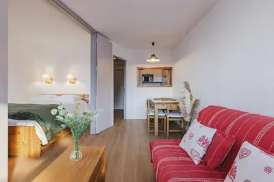 a living room with a red couch and a bedroom at Chamois - Cosy 3pax Centre Vue Parking Gare routiere in Chamonix-Mont-Blanc