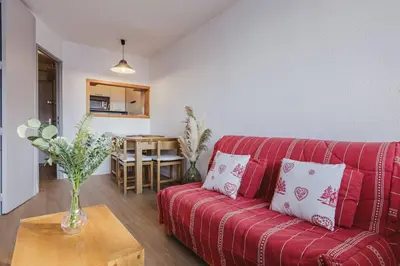 a red couch in a living room with a table at Chamois - Cosy 3pax Centre Vue Parking Gare routiere in Chamonix-Mont-Blanc