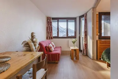 a living room with a table and a red chair at Chamois - Cosy 3pax Centre Vue Parking Gare routiere in Chamonix-Mont-Blanc