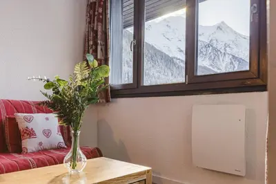 a vase of flowers on a table in front of a window at Chamois - Cosy 3pax Centre Vue Parking Gare routiere in Chamonix-Mont-Blanc