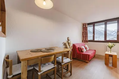 a dining room with a table and a red couch at Chamois - Cosy 3pax Centre Vue Parking Gare routiere in Chamonix-Mont-Blanc