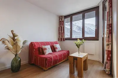 a living room with a red couch and a window at Chamois - Cosy 3pax Centre Vue Parking Gare routiere in Chamonix-Mont-Blanc
