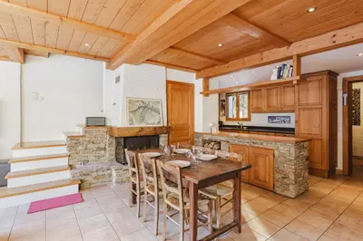 a kitchen with a table and a stone fireplace at Beugeant - Cosy Chalet 140m2 Vues Calme Garage in Chamonix-Mont-Blanc