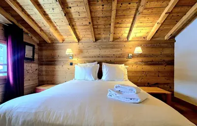 a bedroom with a white bed with a wooden ceiling at Charming duplex in Hameau des Pistes ski in ski out in Megève