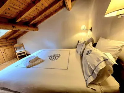 a bedroom with a white bed with a wooden ceiling at Charming duplex in Hameau des Pistes ski in ski out in Megève