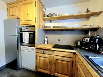 a kitchen with wooden cabinets and a white refrigerator at Charming duplex in Hameau des Pistes ski in ski out in Megève