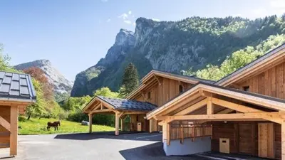 a large wooden building with a horse in the background at Demi-chalet meublé de tourisme 4 étoiles in Samoëns
