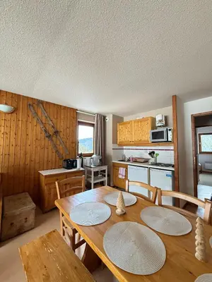 a kitchen with a wooden table and wooden cabinets at Appartement face aux pistes Morillon 1100 in Morillon