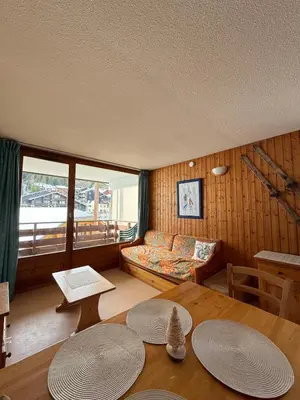 a living room with a couch and a table at Appartement face aux pistes Morillon 1100 in Morillon